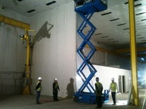 Imagem de Construção de Sala Limpa, paredes e forros, profissionais e uma plataforma elevatória auxiliando o levantamento de painéis