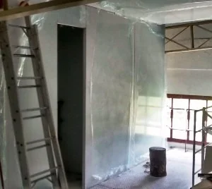 A imagem inicial apresenta uma parede construída a princípio com painéis divisórias para sala limpa em PIR. Da mesma forma, mostra a abertura de vão de pasagem para instalção de porta sala limpa.