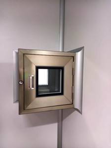 Na imagem, Pass-through para Sala Limpa em aço inóx com acabamento em cantos arredondados. equipamento instalado na junção de duas paredes divisórias.